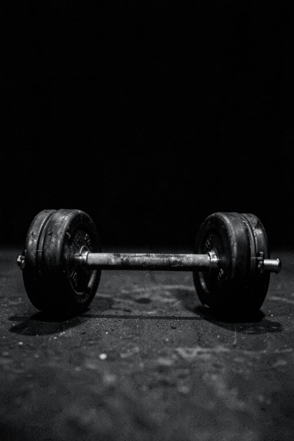 Loaded barbell resting on a dark gym floor