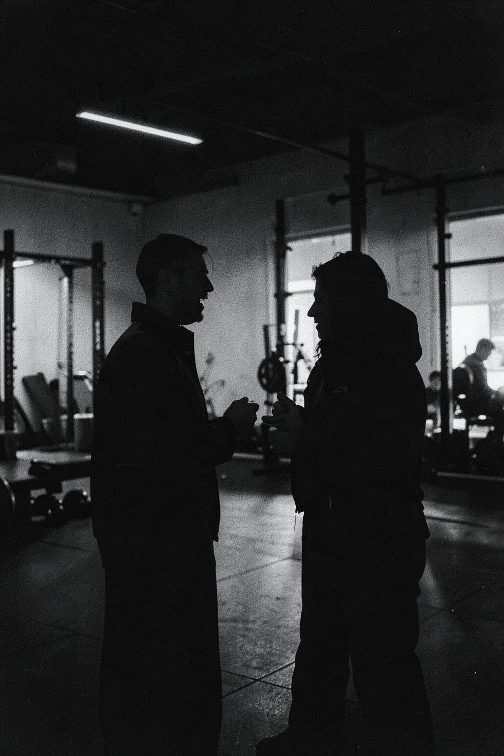 Two people in conversation in a dimly lit gym